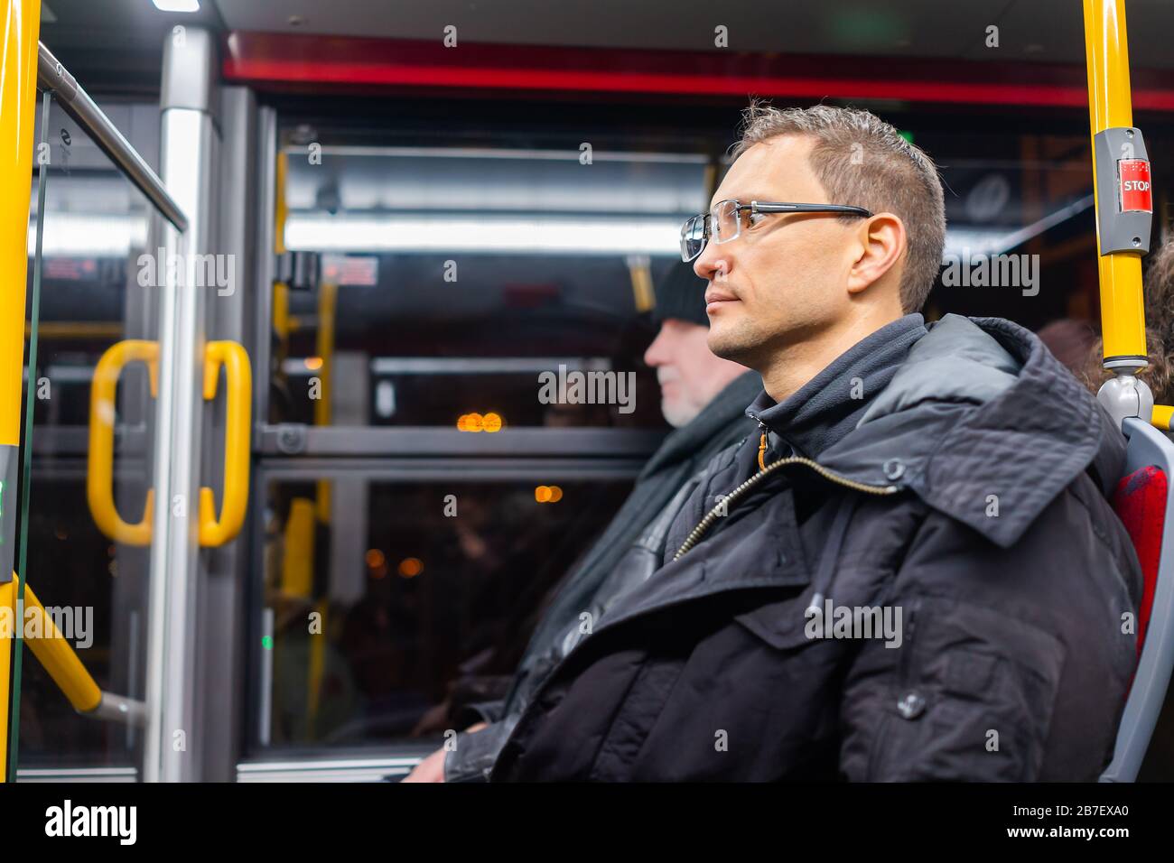Jeune homme en manteau d'hiver et en chandail voyageant en bus de transport public de l'aéroport international de Chopin à Varsovie, Pologne Banque D'Images