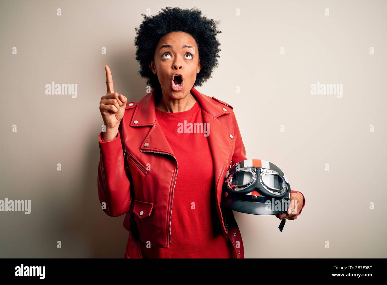 Jeune femme afro-cycliste africaine avec des cheveux bouclés tenant un  casque de moto étonné et surpris de regarder et de pointer avec les doigts  et Photo Stock - Alamy