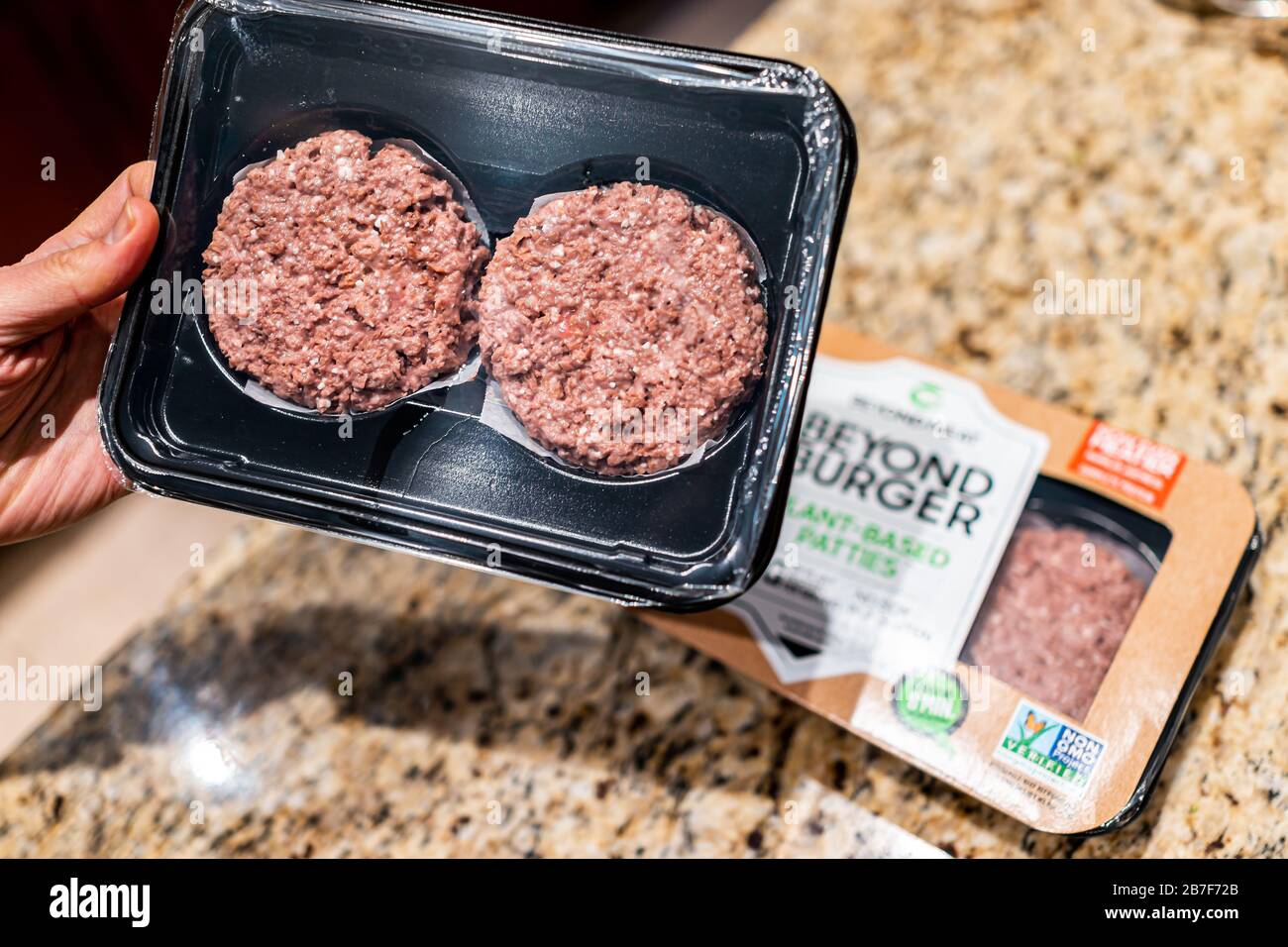 Herndon, États-Unis - 3 février 2020: Homme main mâle tenant cru non cuit Au-Delà du paquet Burger de viandes à base de plantes avec des hamburgers au-dessus du comptoir de cuisine Banque D'Images