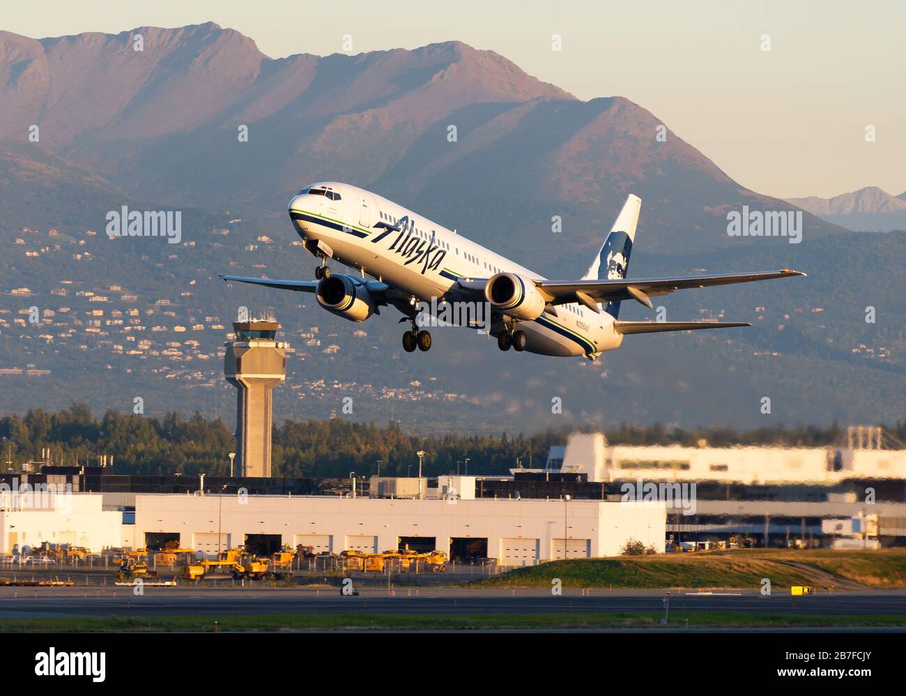 Le Boeing 737 d'Alaska Airlines quitte l'aéroport d'Anchorage en face de la tour de contrôle de la circulation aérienne et des montagnes. Aéronefs immatriculés comme N305 AS. Banque D'Images