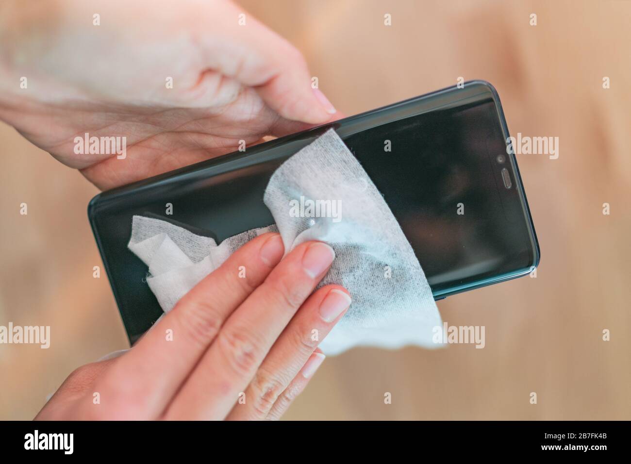 Nettoyage de l'écran du téléphone nettoyage de la femme éliminant les germes avec des lingettes antibactériennes humides pour la prévention du coronavirus du virus corona COVID-19. Banque D'Images