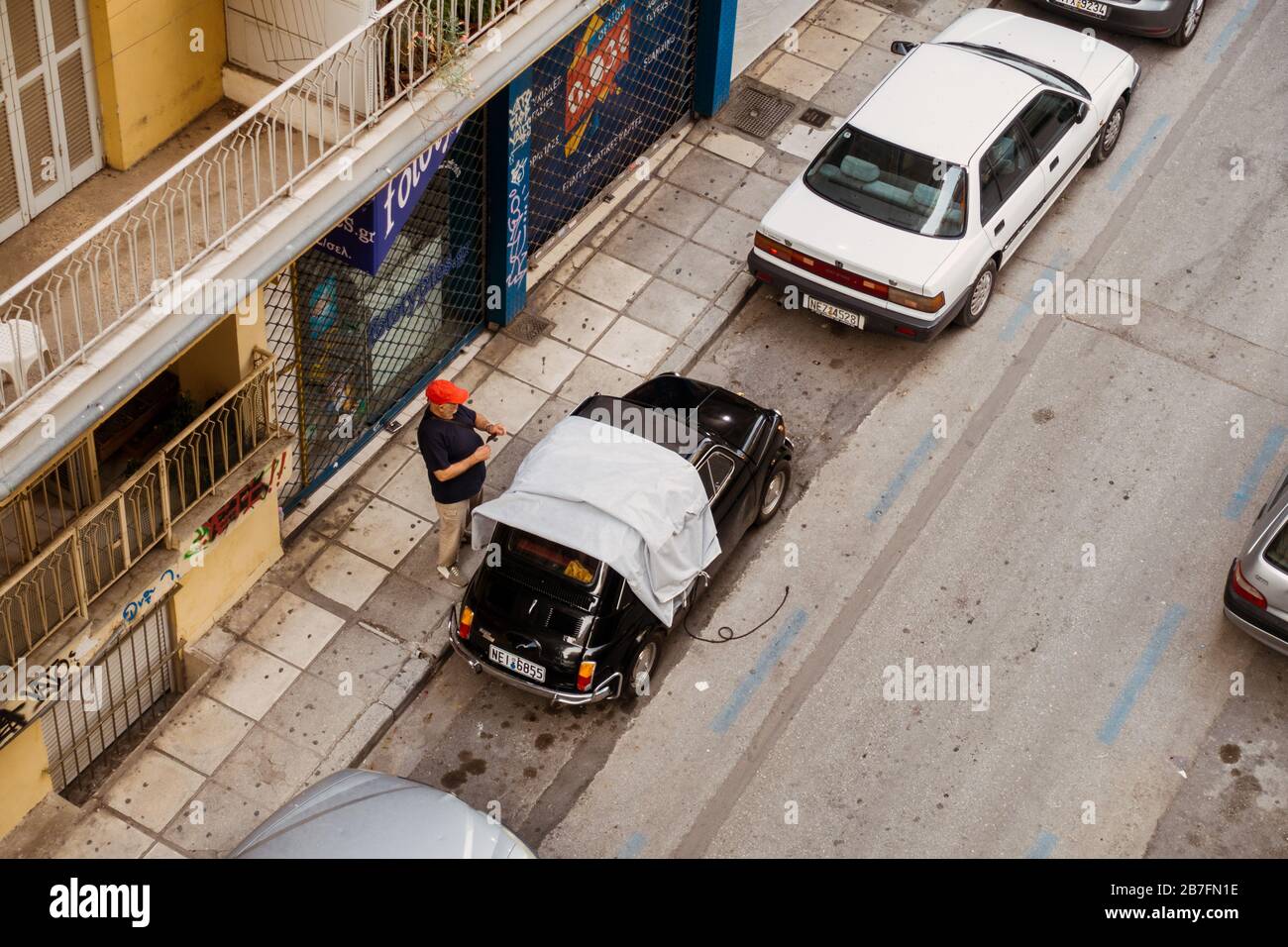 Un homme retire une couverture protectrice de sa Fiat 500 Bambino classique à Thessalonique, Grèce Banque D'Images