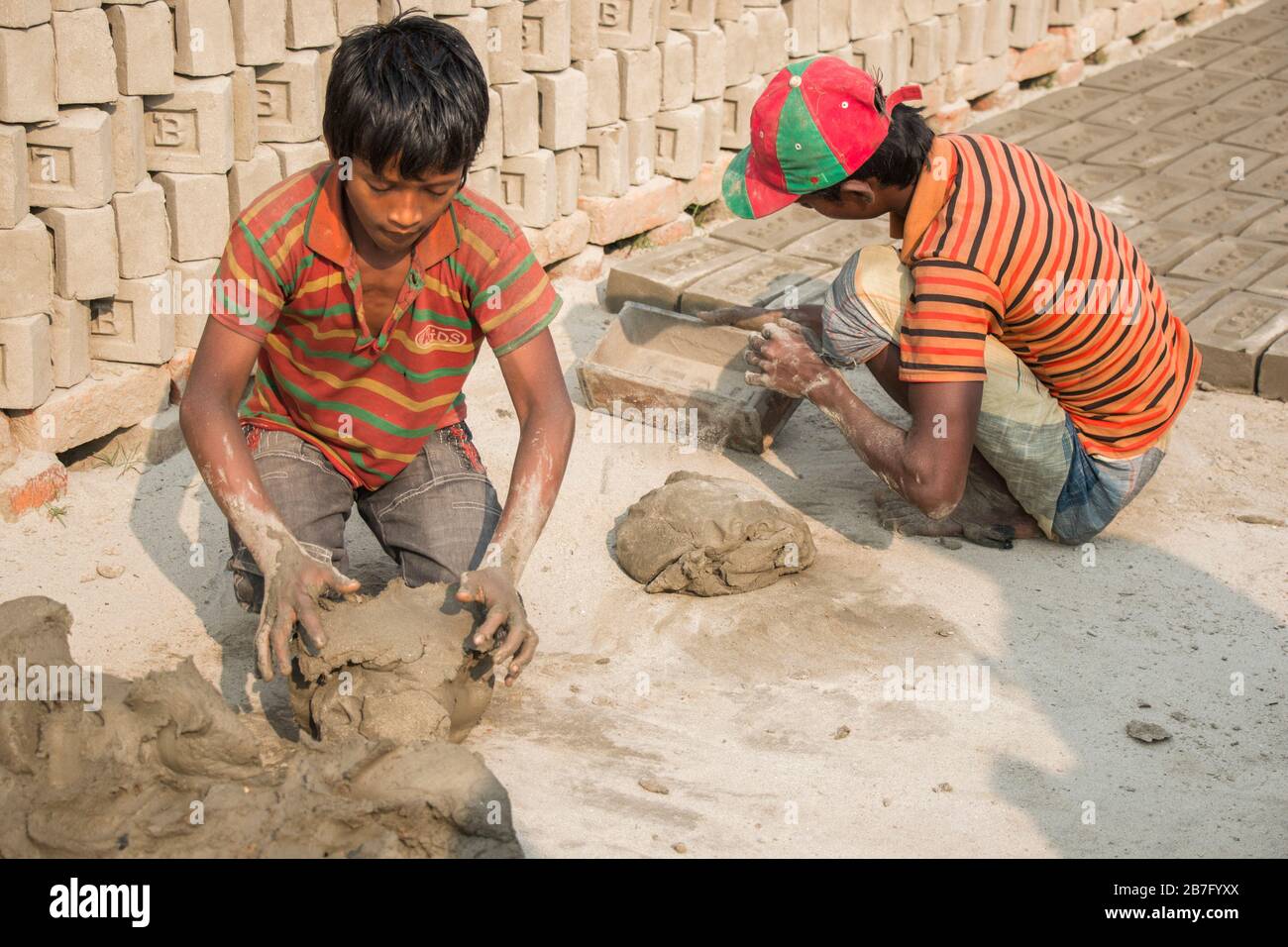 Un travail d'enfant au Bangladesh travaille dans une brique déposée sous un jour ensoleillé. Bien que le travail des enfants soit limité dans cette industrie, il travaille pour la nourriture. Banque D'Images
