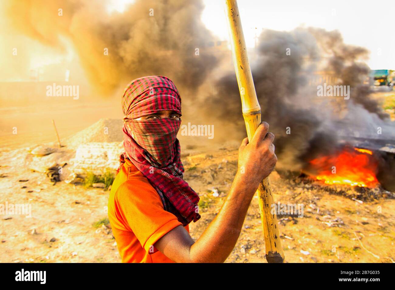 Les ouvriers de la construction chauffent des bitumeux dans une journée chaude ensoleillée d'été sans masque de protection approprié ou gants à main dans l'extrême fumée. Banque D'Images