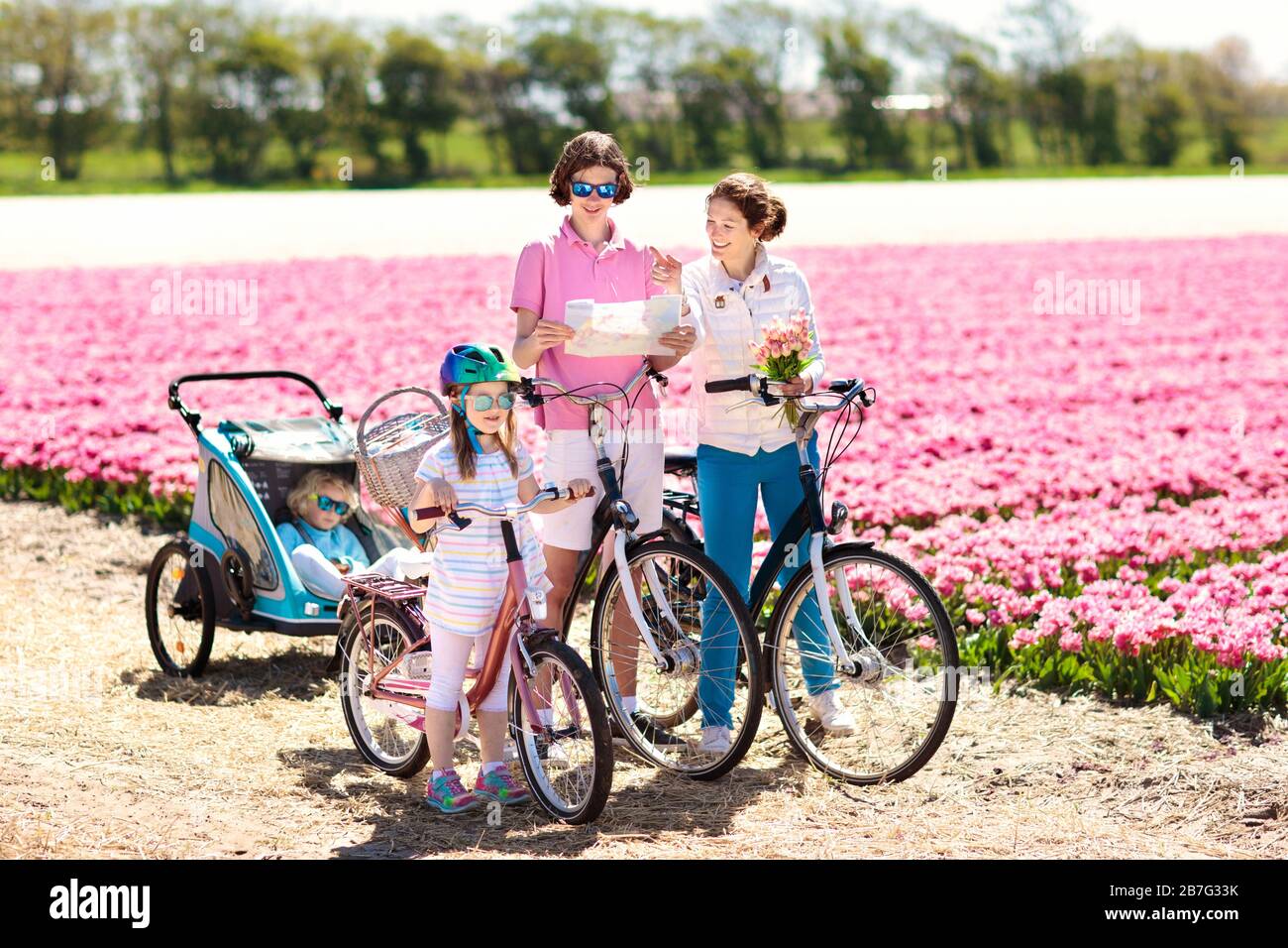 Heureux famille néerlandaise riding bicycle in tulip champs de fleurs en Hollande. Mère et enfants sur des vélos à la floraison des tulipes en Hollande. Bébé en vélo. Banque D'Images