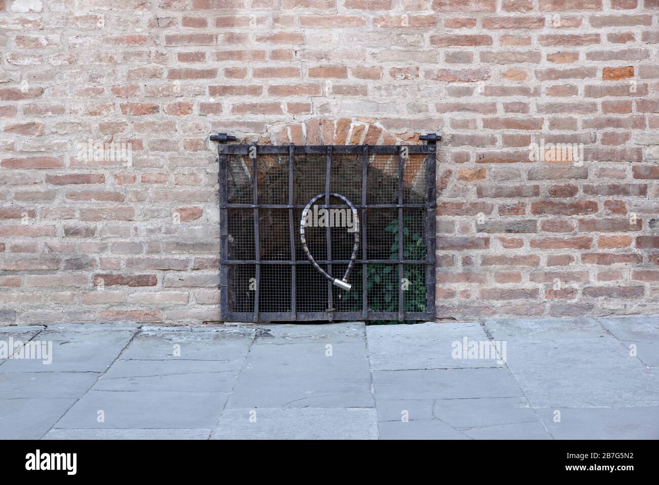 Fenêtre fermée avec grille métallique, dans la façade d'une ancienne maison négligée Banque D'Images