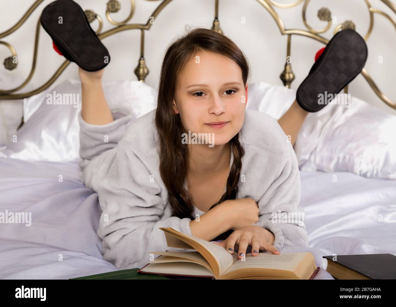 une jeune fille étudiante lit un livre en étant couché sur un lit pour  faire ses devoirs Photo Stock - Alamy