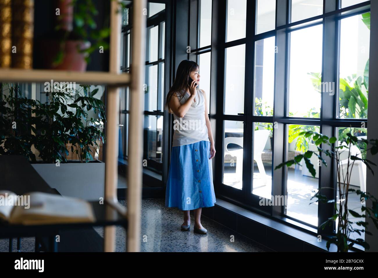 Femme asiatique ayant un appel téléphonique et regardant à l'extérieur Banque D'Images