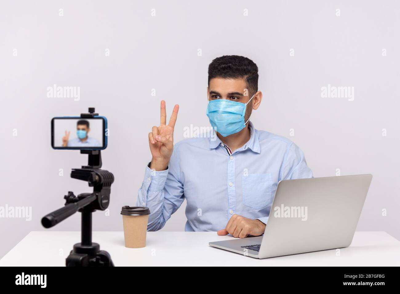 L'homme dans un masque hygiénique gestuelle victoire rendant la vidéo sur la récupération après la grippe, l'infection de coronavirus, donnant des conseils sur l'utilisation de protéger le filtre contre le conta Banque D'Images