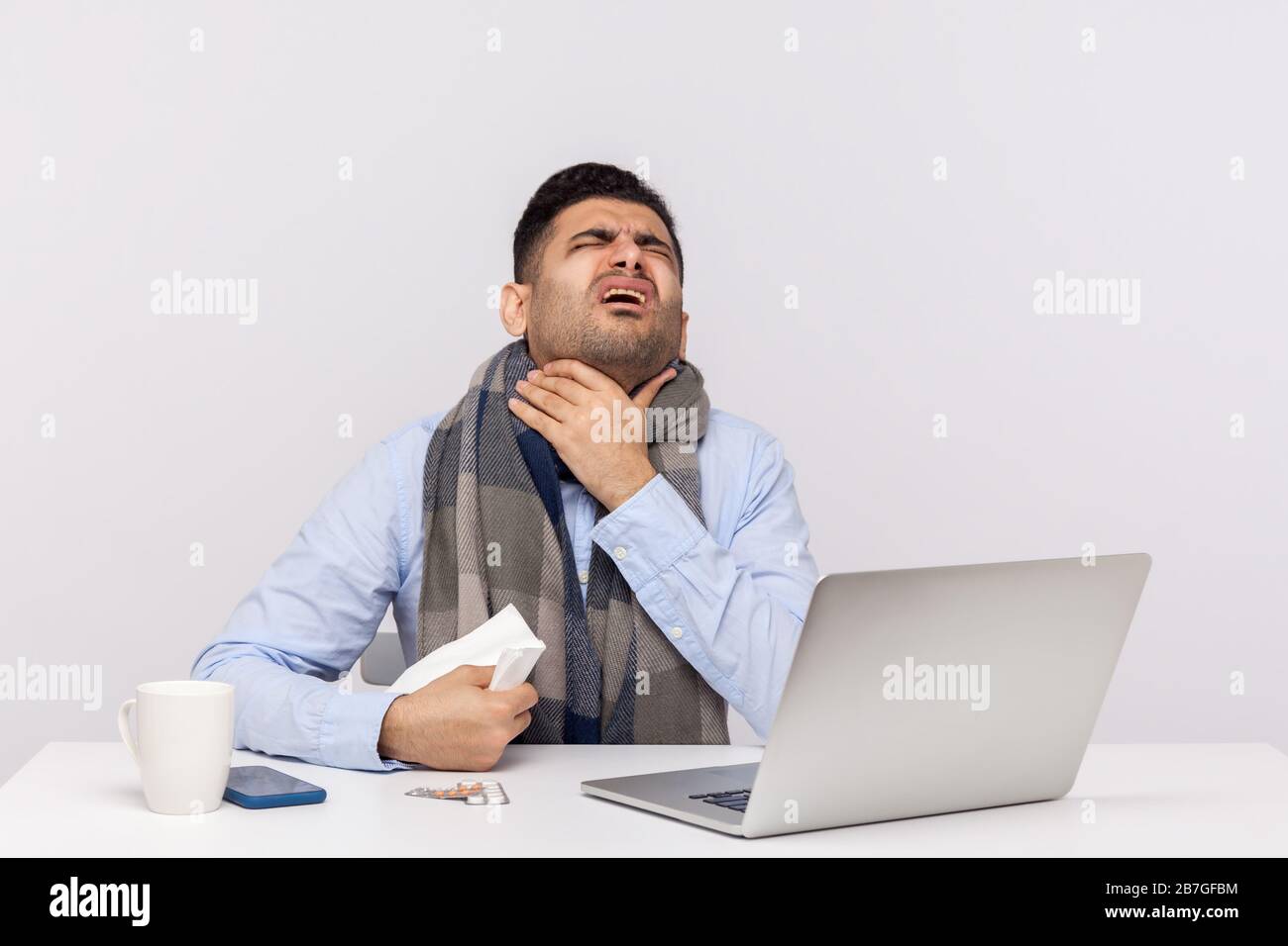 Homme d'affaires de grippe-malade dans le foulard souffrant de maux de gorge, assis au bureau se sentant mal, risque d'infection de coronavirus, maladie contagieuse 2019-nCoV, in Banque D'Images