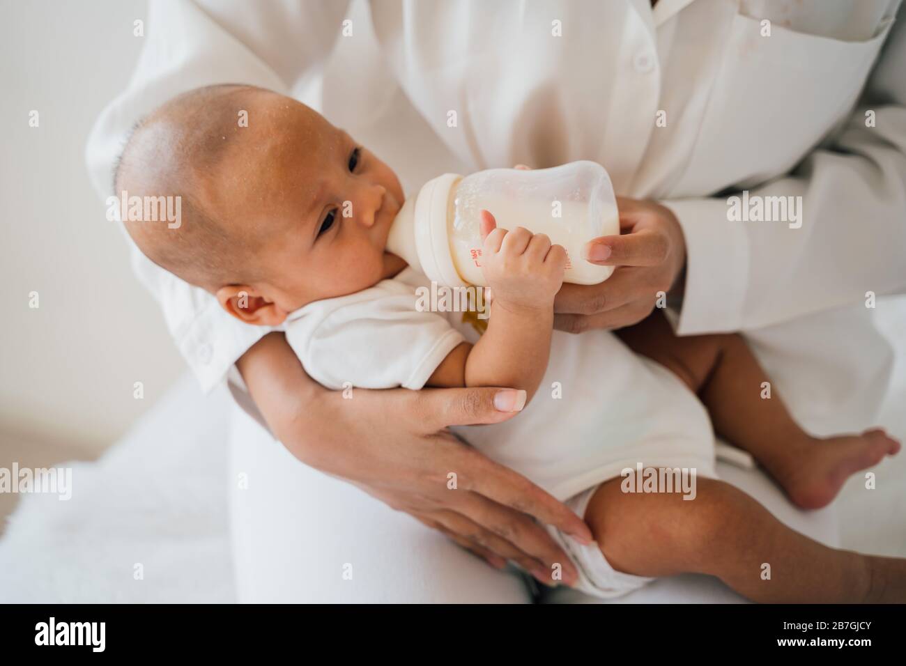 Mère tenant et nourrissant un bébé nouveau-né de la bouteille à la maison Banque D'Images