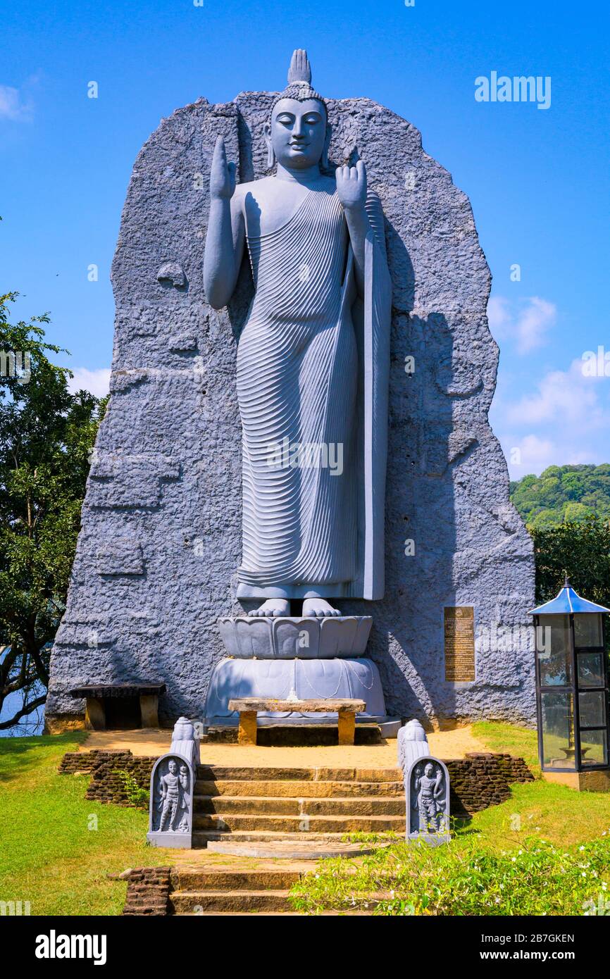 Asie du Sud Sri Lanka géant moderne gris gris sculpture en pierre de Bouddha Garde étapes de pierre escaliers par réservoir d'irrigation autel petite statue blanche Banque D'Images