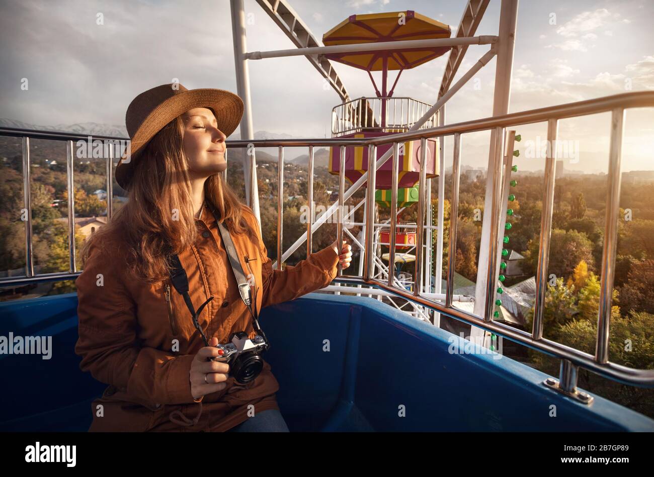 Femme avec chapeau et vintage camera à la cabine de la grande roue dans le parc de l'automne au coucher du soleil Banque D'Images