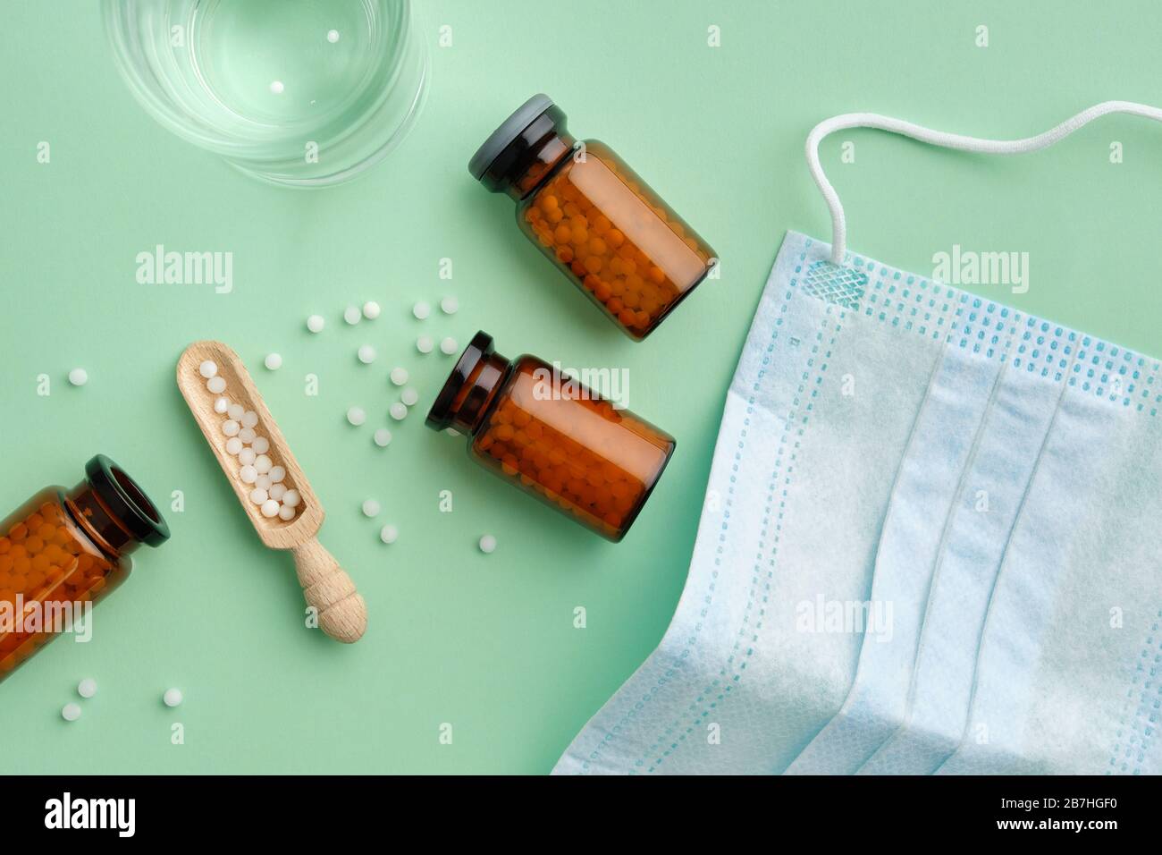 Flacons de granules homéopathiques, verre à eau pour la préparation de solutions médicinales, masque médical de protection. Vue de dessus. Banque D'Images