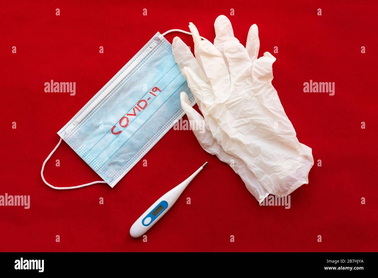 Masque de protection, thermomètre et gants chirurgicaux sur fond rouge. Concept de protection contre les virus et les maladies. Banque D'Images