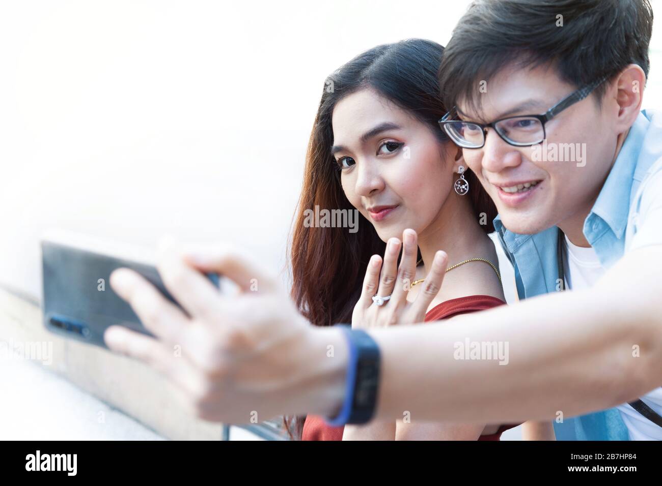 jeune homme asiatique utilisant un smartphone prenant des photos avec sa petite amie après avoir engagé la proposition et sourire heureuse femme et montrant son anneau de mariage. heureux Banque D'Images
