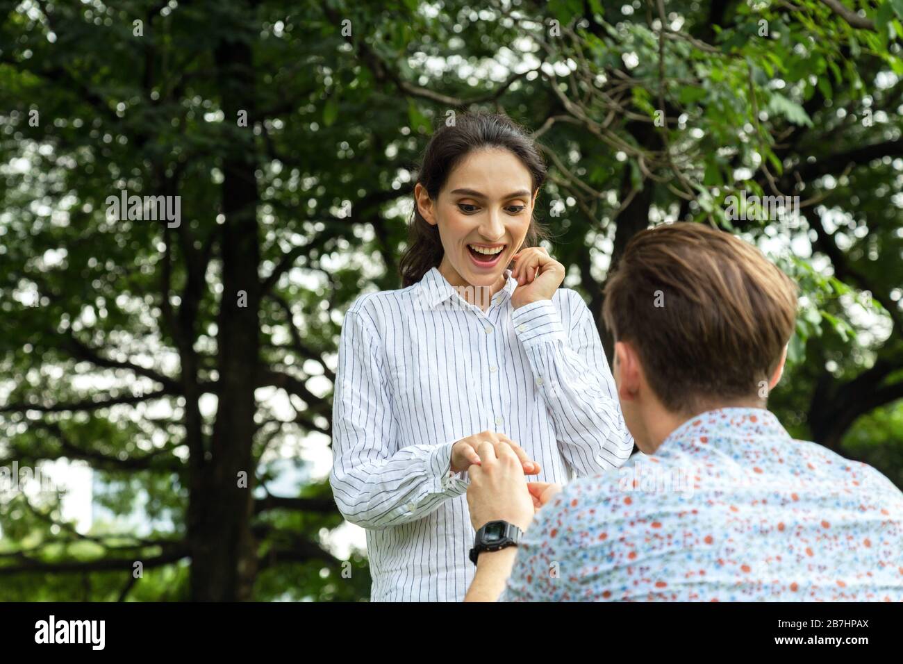 surprise jeune femme et sourire pendant que son petit ami mariage propose dans le parc. me marier. amour, couple, date, mariage - concept Banque D'Images