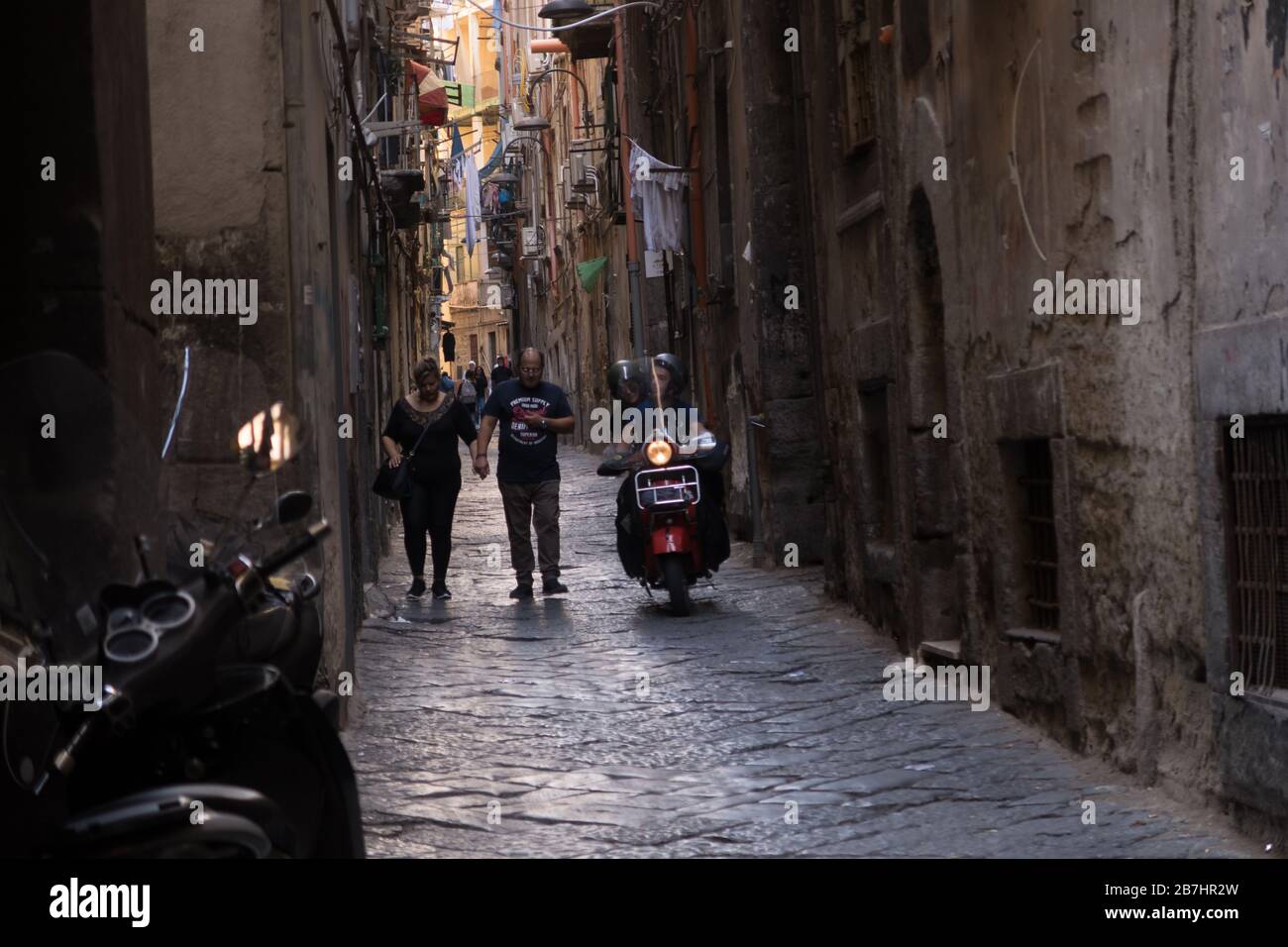 Piétons et scooters partageant une rue étroite de Naples, Italie Banque D'Images