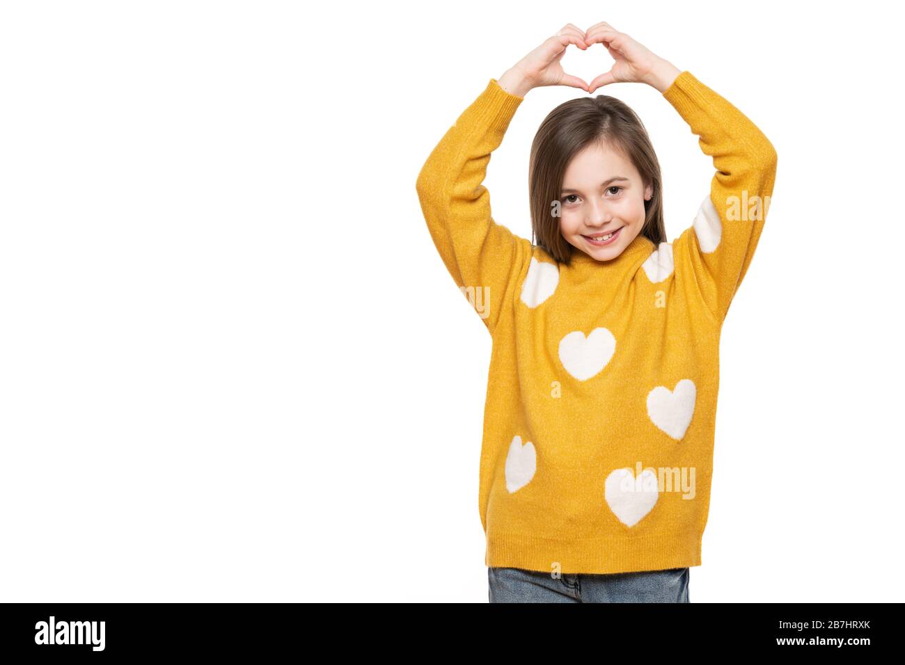 Studio portrait d'une petite fille sur fond blanc faisant un geste de coeur avec ses mains. Promotion d'un enfant, aide humanitaire, coopération, don Banque D'Images