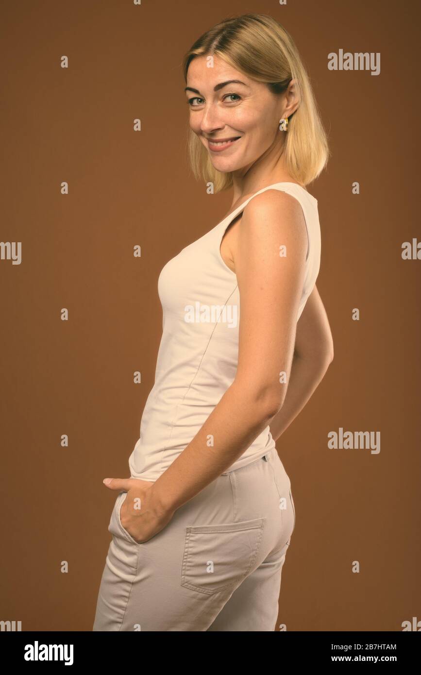 Studio shot of beautiful businesswoman avec de courts cheveux blonds contre fond brun Banque D'Images