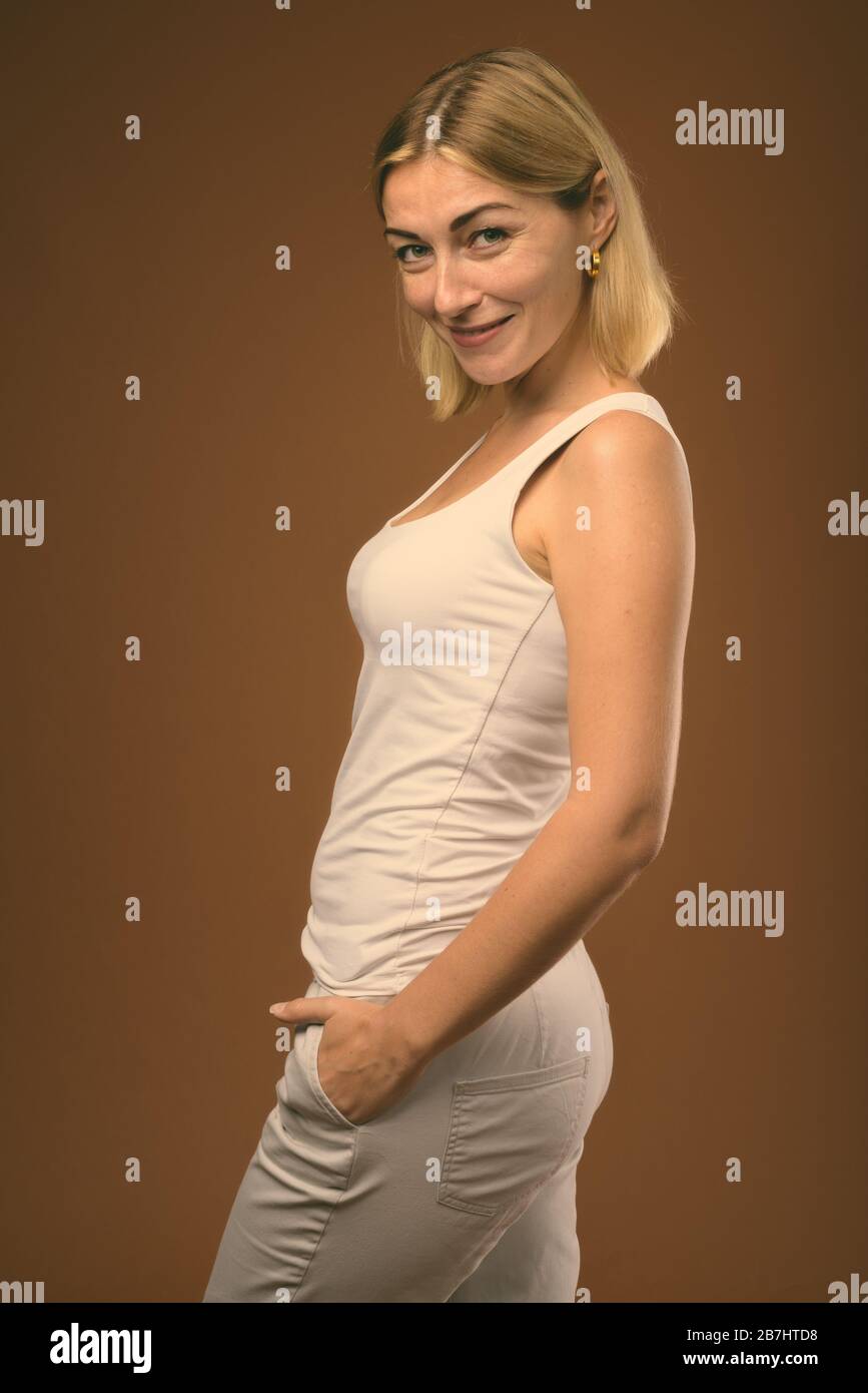 Studio shot of beautiful businesswoman avec de courts cheveux blonds contre fond brun Banque D'Images