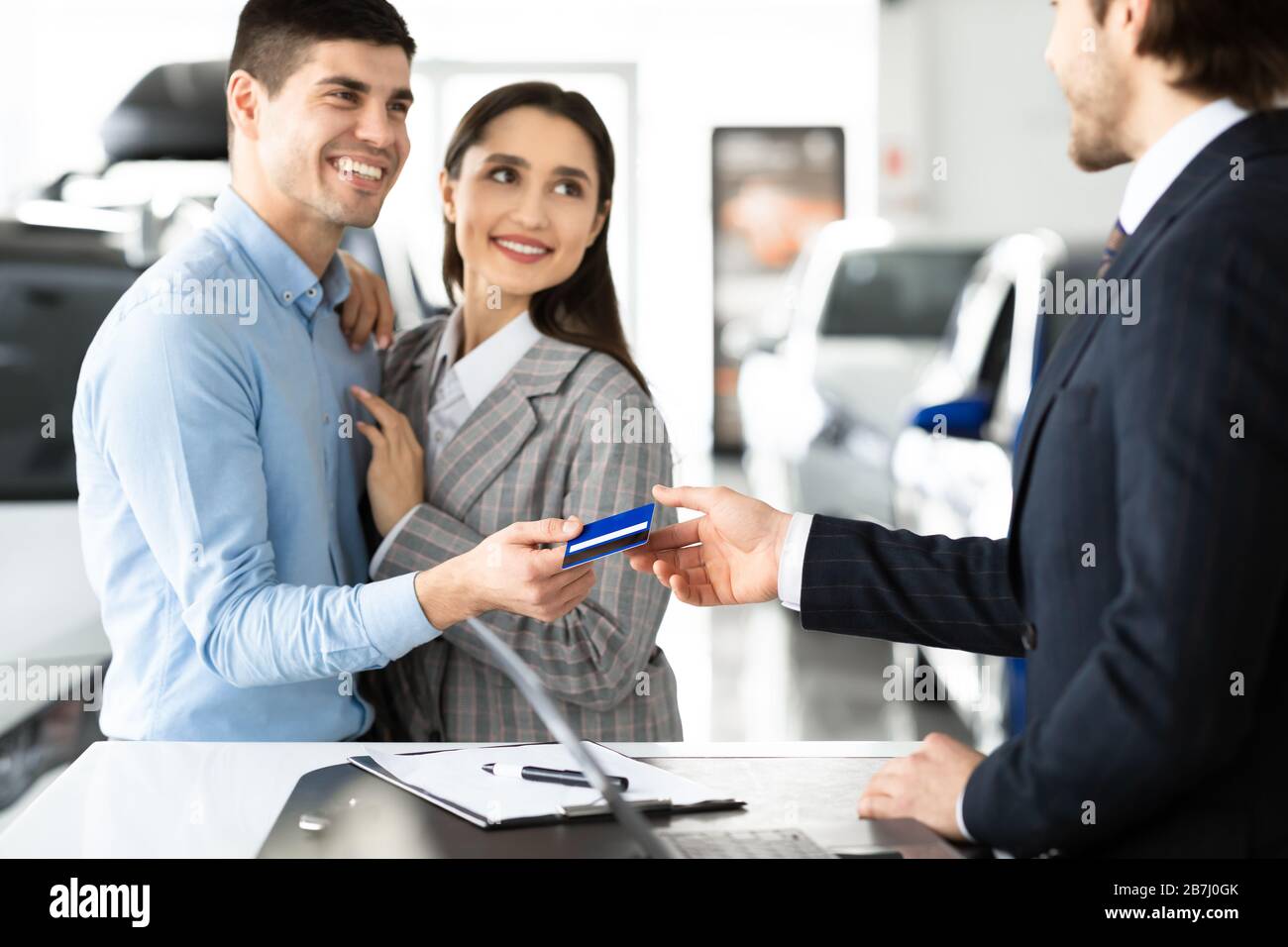 Couple d'achat de voiture donnant la carte de crédit au vendeur Banque D'Images