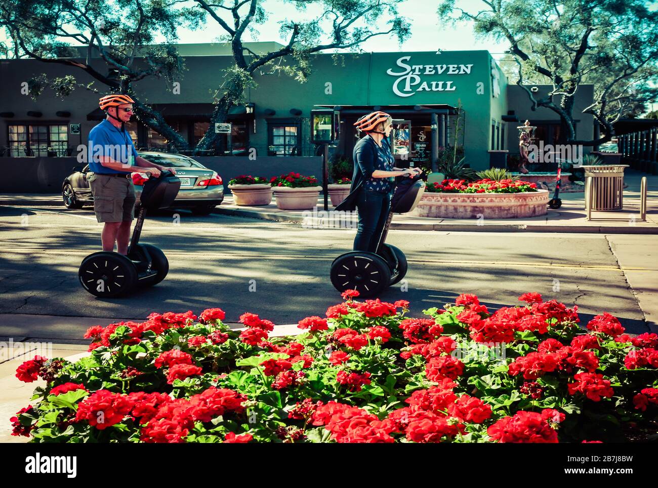 Premier plan de mendias rouges avec une femme caucasienne et un homme portant des casques orange à cheval Segway Personal Transporters dans la vieille ville de Scottsdale, AZ, États-Unis Banque D'Images