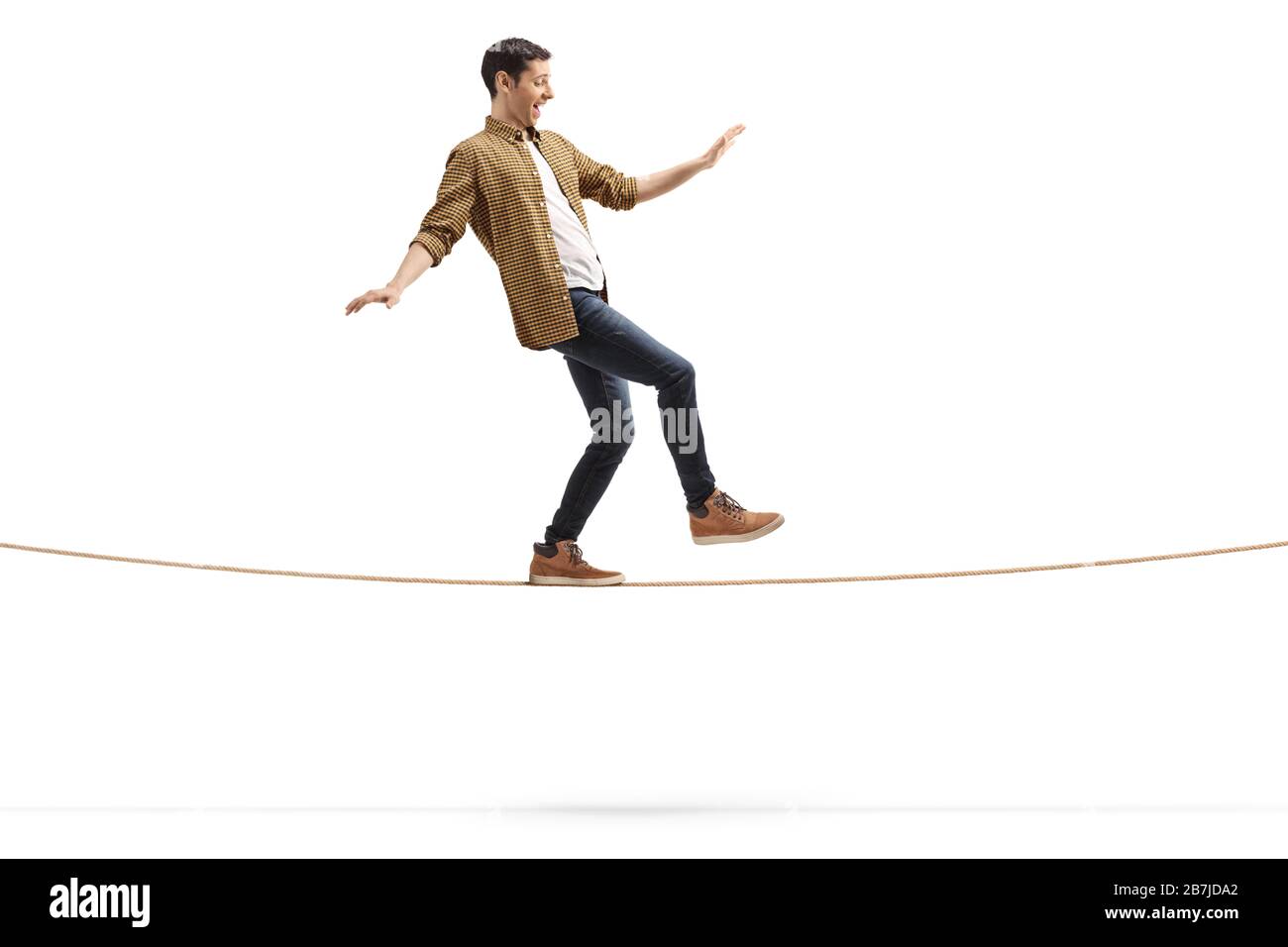 Photo de profil pleine longueur d'un jeune homme marchant sur une corde isolée sur fond blanc Banque D'Images