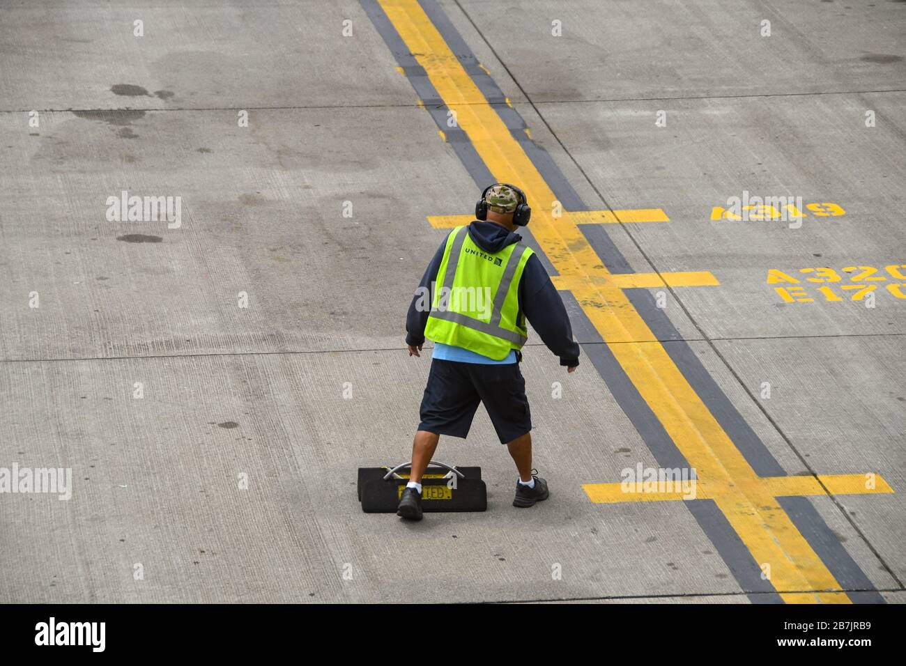 AÉROPORT DE SEATTLE TACOMA, WA, États-Unis - JUIN 2018 : travailleur de l'aéroport avec gilet haute vis et protecteurs d'oreilles à l'aéroport de Seattle Tacoma, et un ensemble de cales de roue Banque D'Images