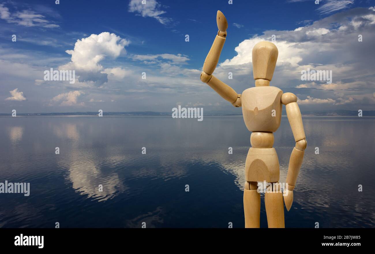 Mannequin humain en bois dans l'acte de salutation avec un assaisonnement avec des nuages blancs importants reflétés comme arrière-plan Banque D'Images