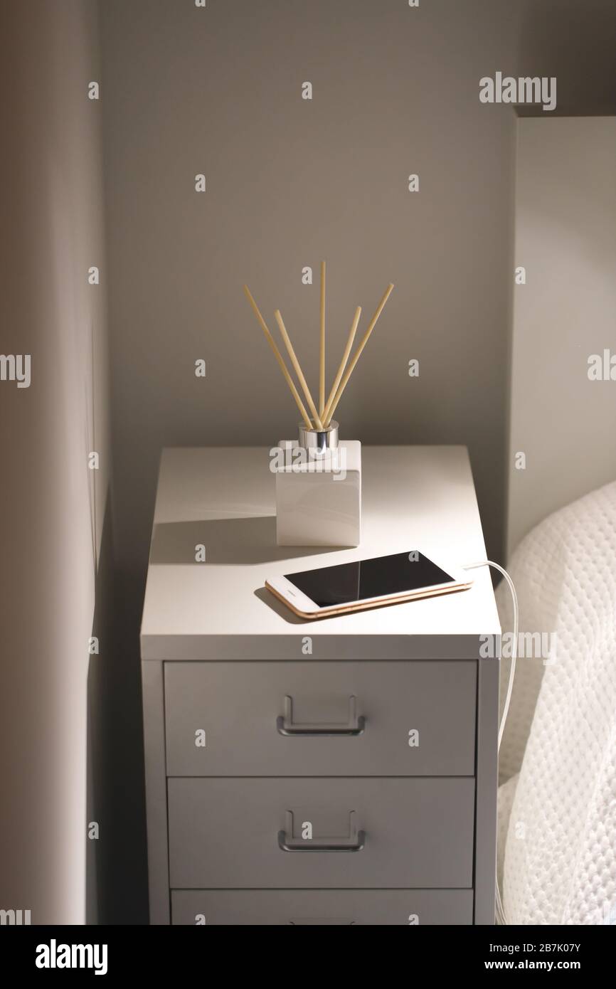 Désodorisant à roseau aromatique et smartphone sur la table de chevet la nuit à la maison. Banque D'Images