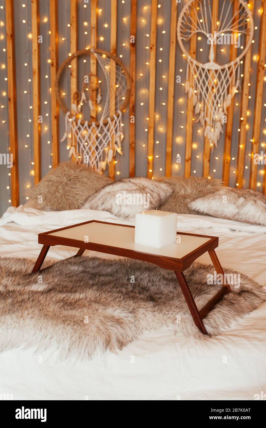Table en bois vide plateau de petit-déjeuner dans le lit. Chambre Boho, décoration murale en bois avec guirlandes, lampes et trancheuses de rêve. Banque D'Images