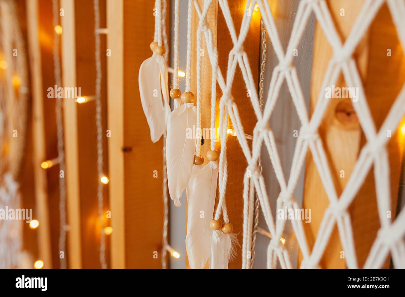 Une partie de la décoration Ethno pour le mur du Dreamcatcher faite de brises, de perles et de plumes tressées sur un mur en bois avec des guirlandes. Banque D'Images