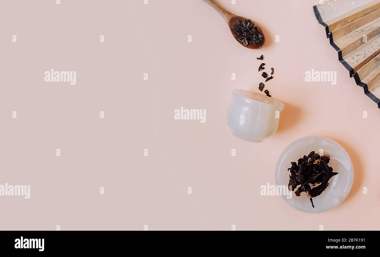 Fête du thé chinois. Granules secs de différents types de thé dans une tasse de pierre blanche, dans des cuillères en bois sur un fond rose délicat. Fond est décorer Banque D'Images