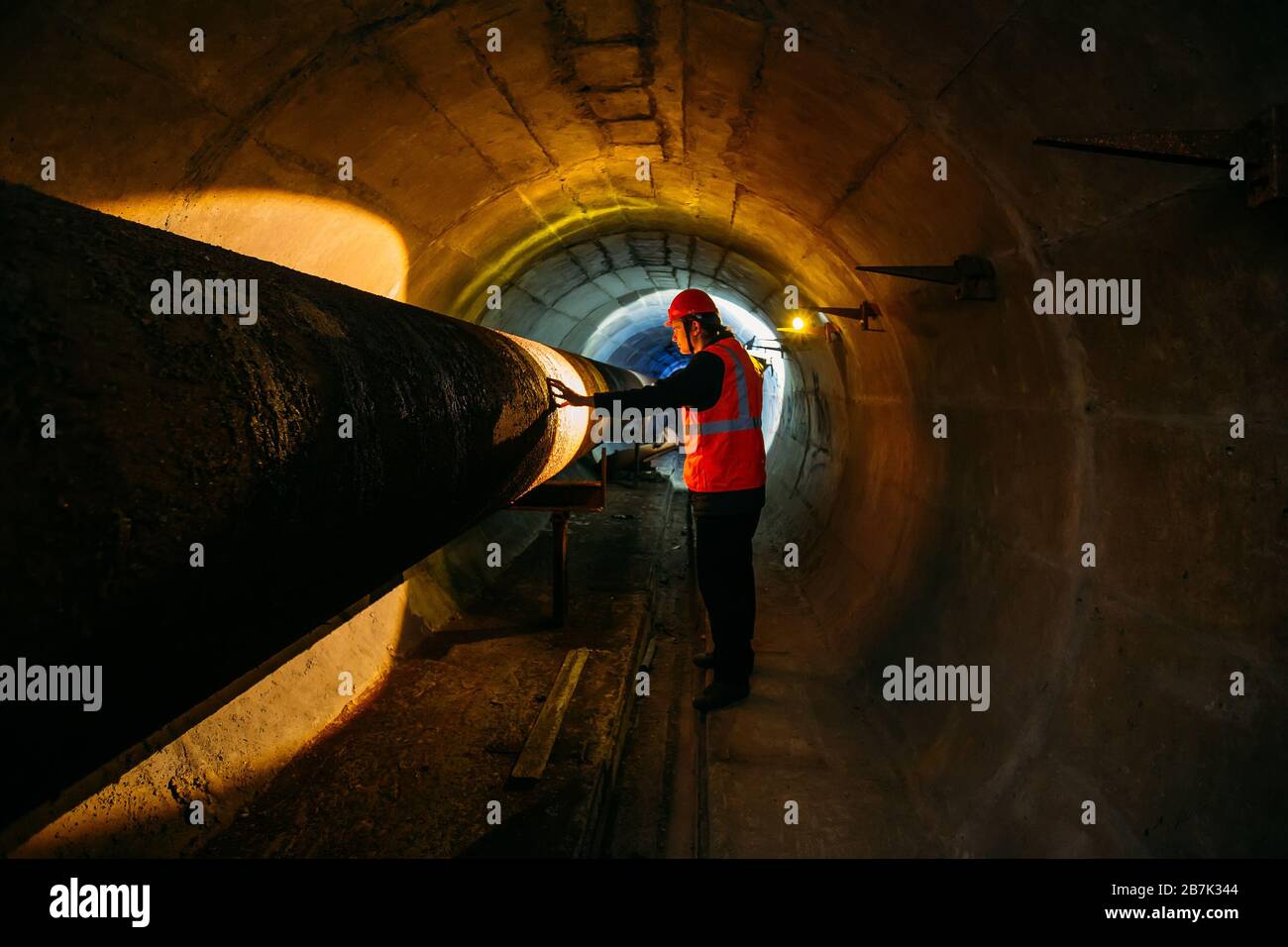 Le travailleur du tunnel examine le pipeline dans le tunnel souterrain. Banque D'Images