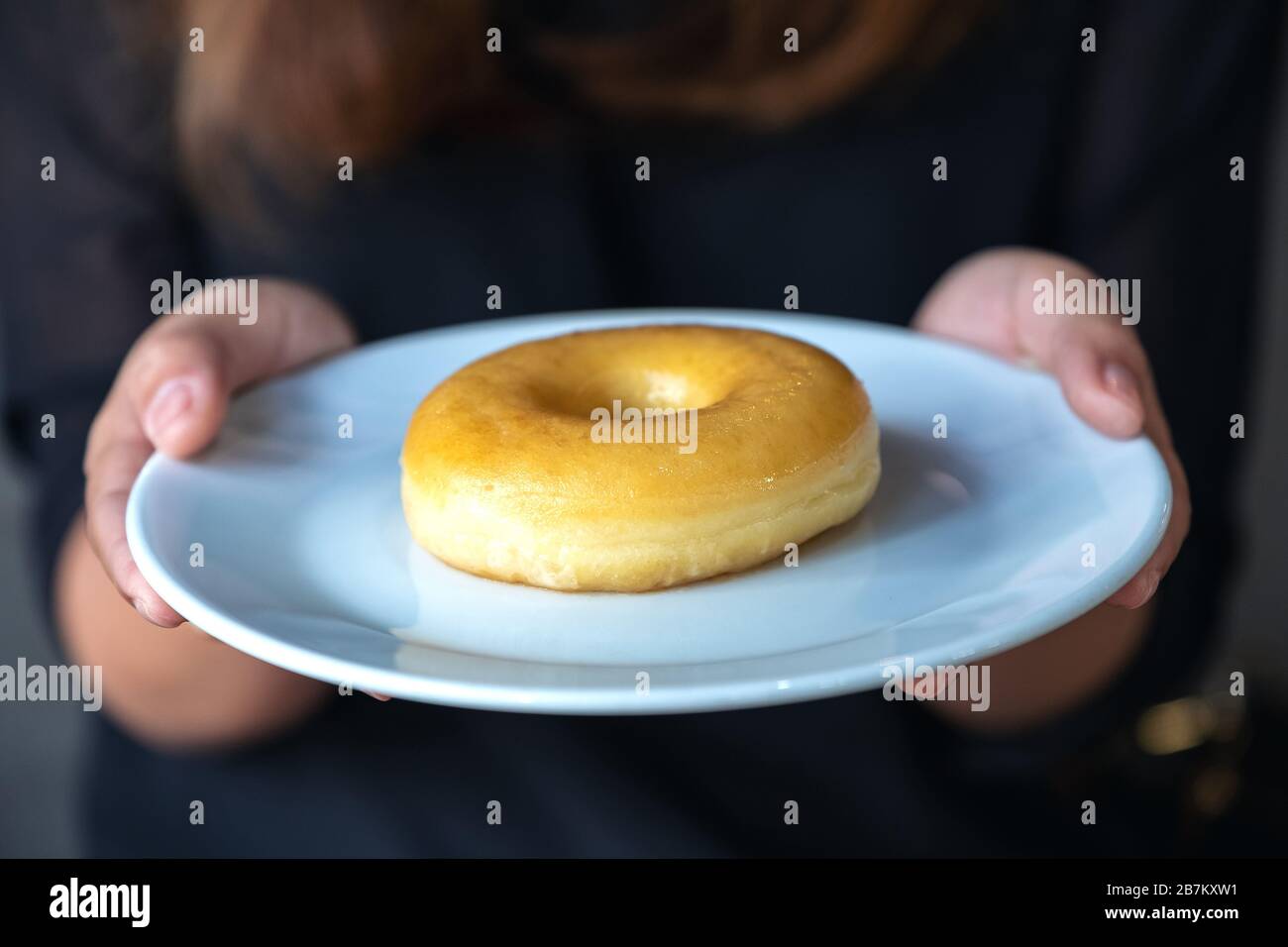 Une femme tenant et montrant une plaque de donut Banque D'Images