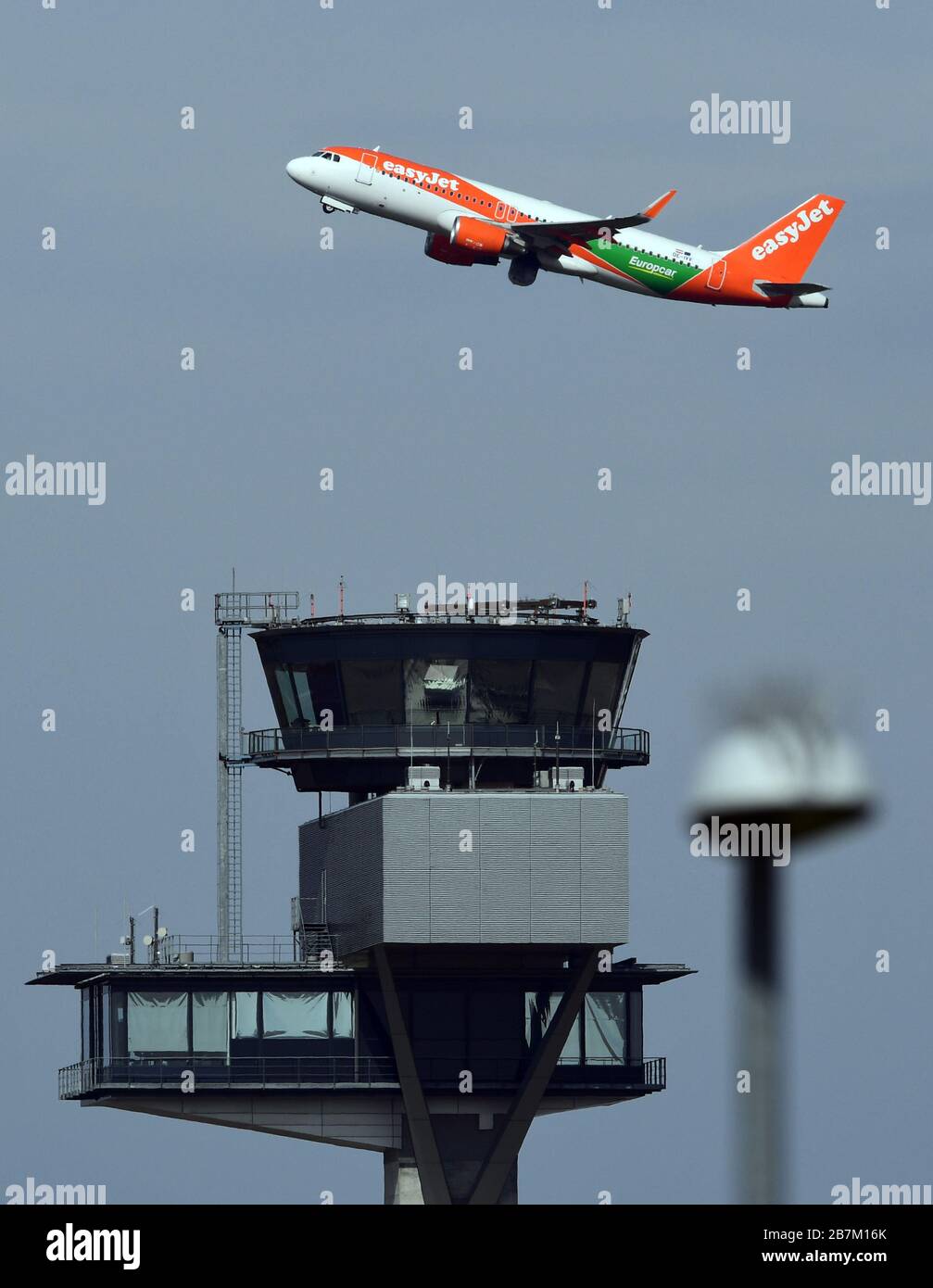 16 mars 2020, Brandenburg, Schönefeld/OT Waltersdorf: Un Airbus A 320 de la compagnie aérienne easyJet avec l'identification OE-IVV et l'étiquette de la société de location de voitures Europcar passe devant la tour de l'aéroport de Berlin-Brandenburg. Photo: Soeren Stache/dpa-Zentralbild/ZB Banque D'Images