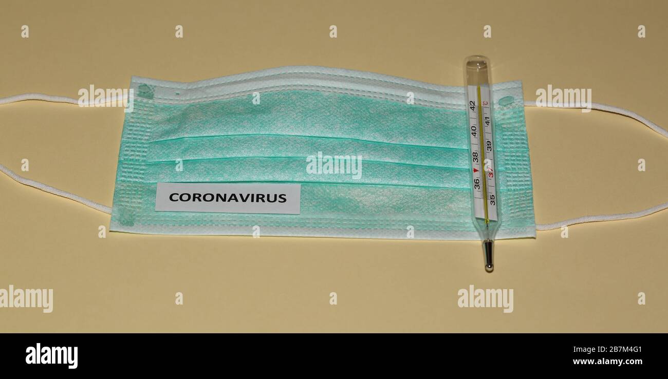 Masque chirurgical de protection simple pour le visage avec son nom DE  CORONAVIRUS et thermomètre médical sur fond de couleur pastel Photo Stock -  Alamy