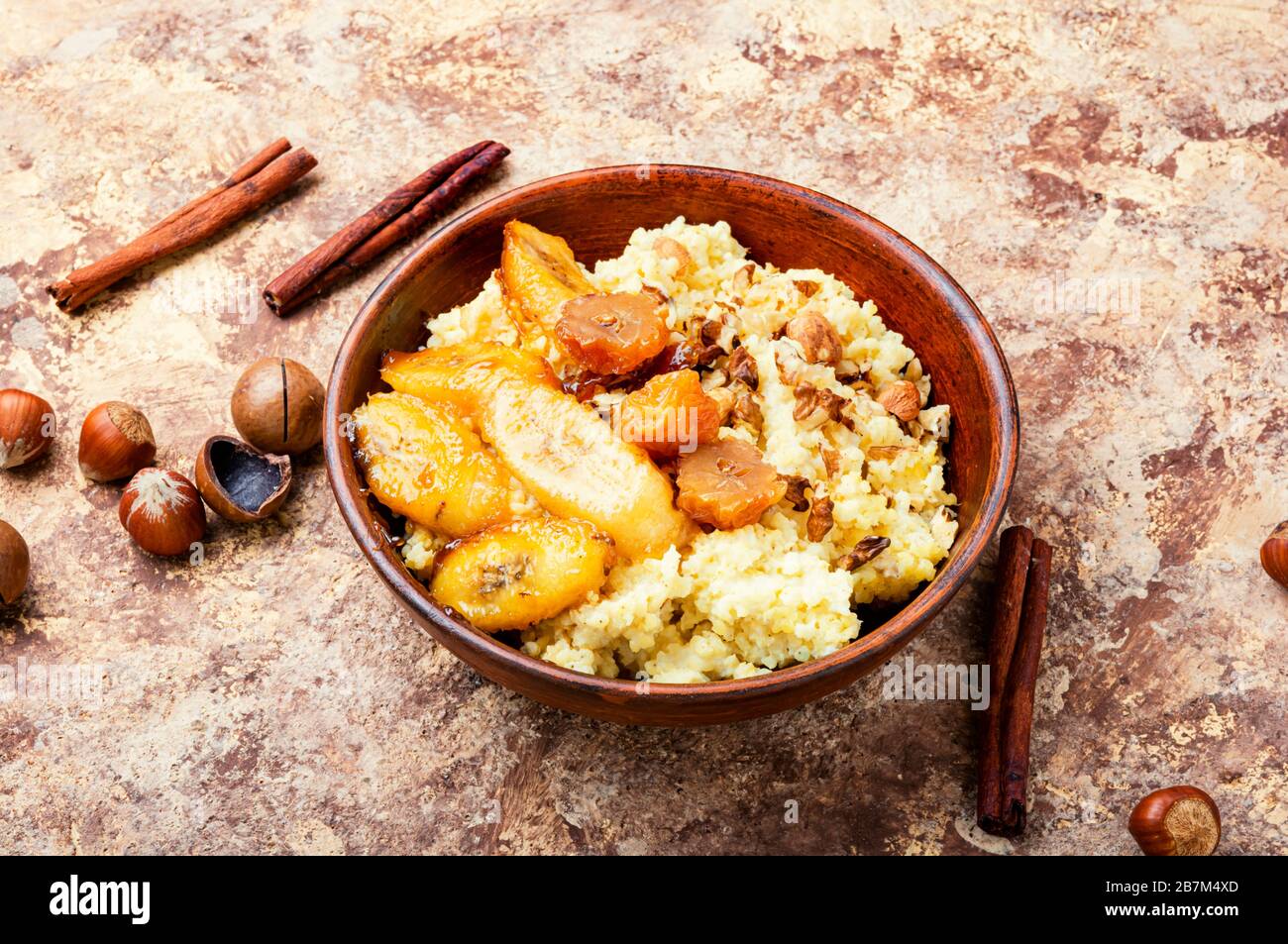 Porridge de millet avec bananes et noix caramélisées. Banque D'Images