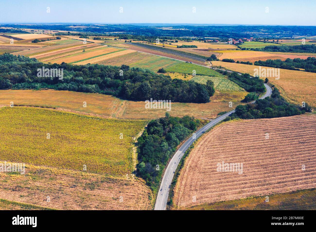 Vue aérienne d'une route de campagne au milieu de champs contre le ciel bleu clair Banque D'Images