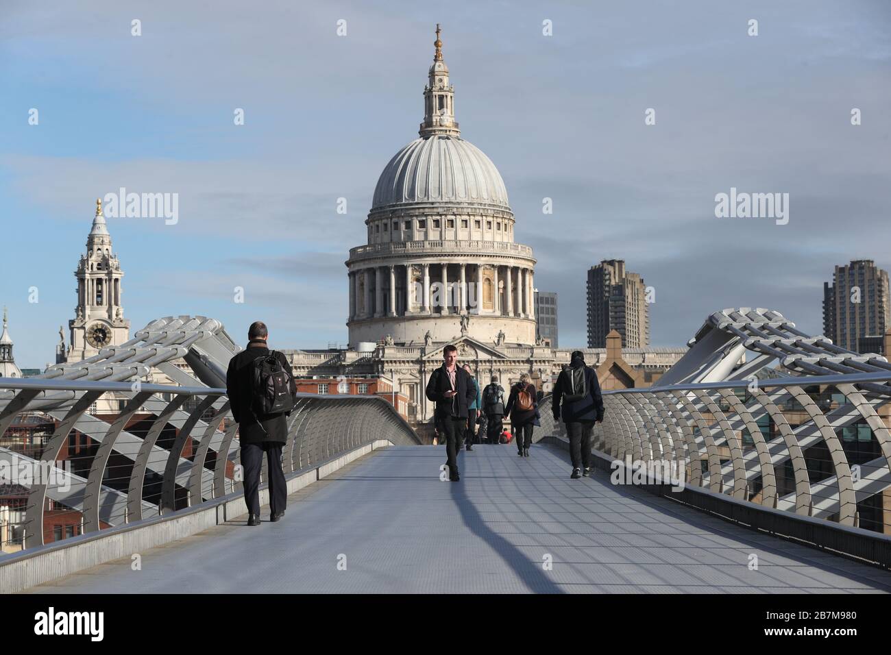 Les navetteurs traversent un pont du millénaire presque vide à Londres, le jour suivant que le Premier ministre Boris Johnson a appelé les gens à rester à l'écart des pubs, des clubs et des théâtres, à travailler à domicile si possible et à éviter tous les contacts non essentiels et à voyager afin de réduire l'impact de la pandémie de coronavirus. Banque D'Images