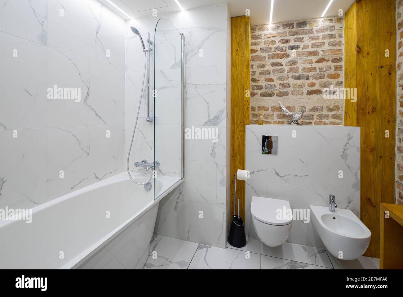 Intérieur moderne et loft de la salle de bains. Bain blanc. Mur de briques. Toilettes et bidet. Banque D'Images