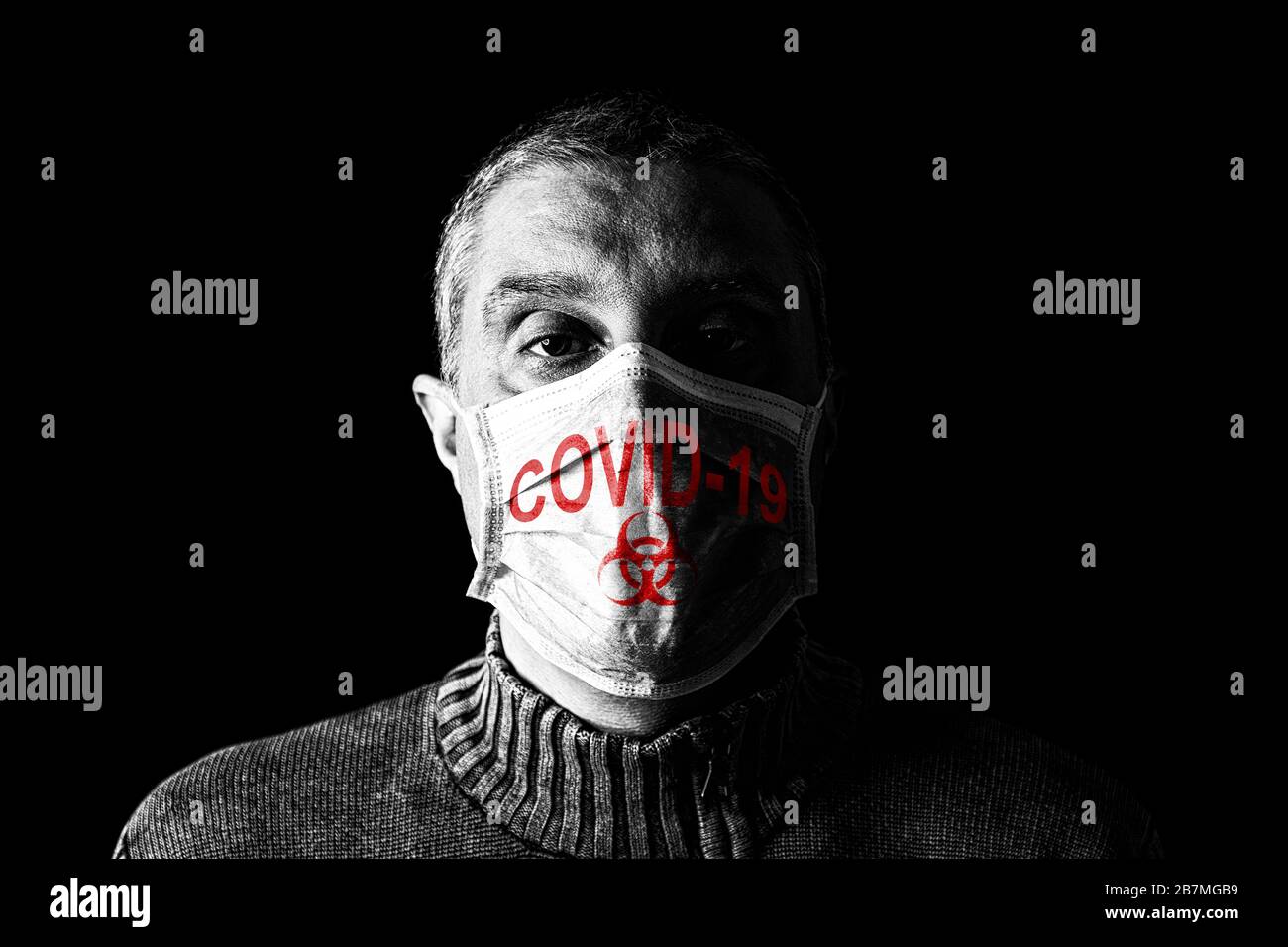 Homme avec masque chirurgical. Biohazard et COVID-19, alias le symbole Coronavirus. Concept de pandémie ou d'épidémie et de peur, de peur ou de danger. Fond noir Banque D'Images