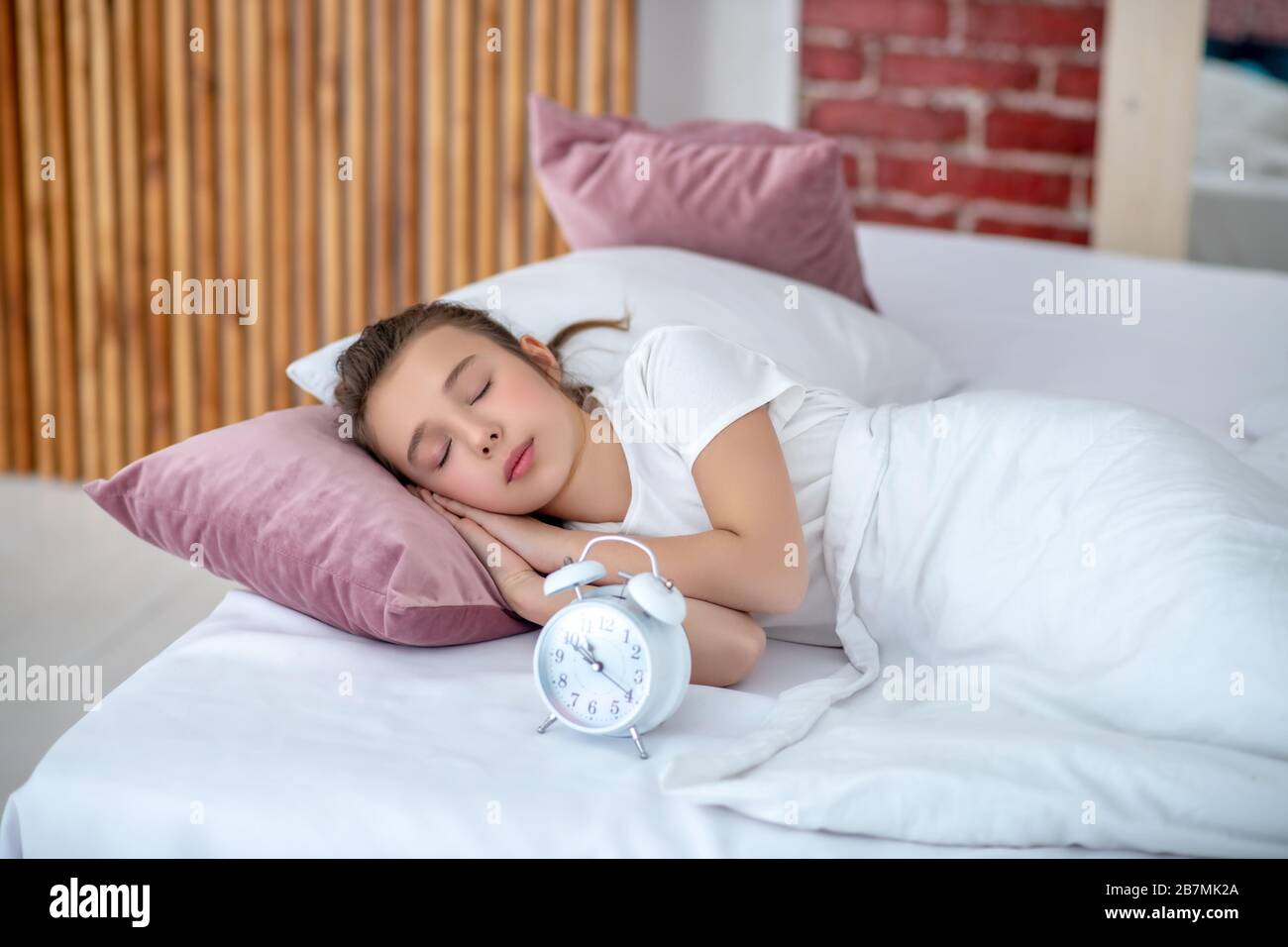 Une jeune fille dormant dans un grand lit. Banque D'Images