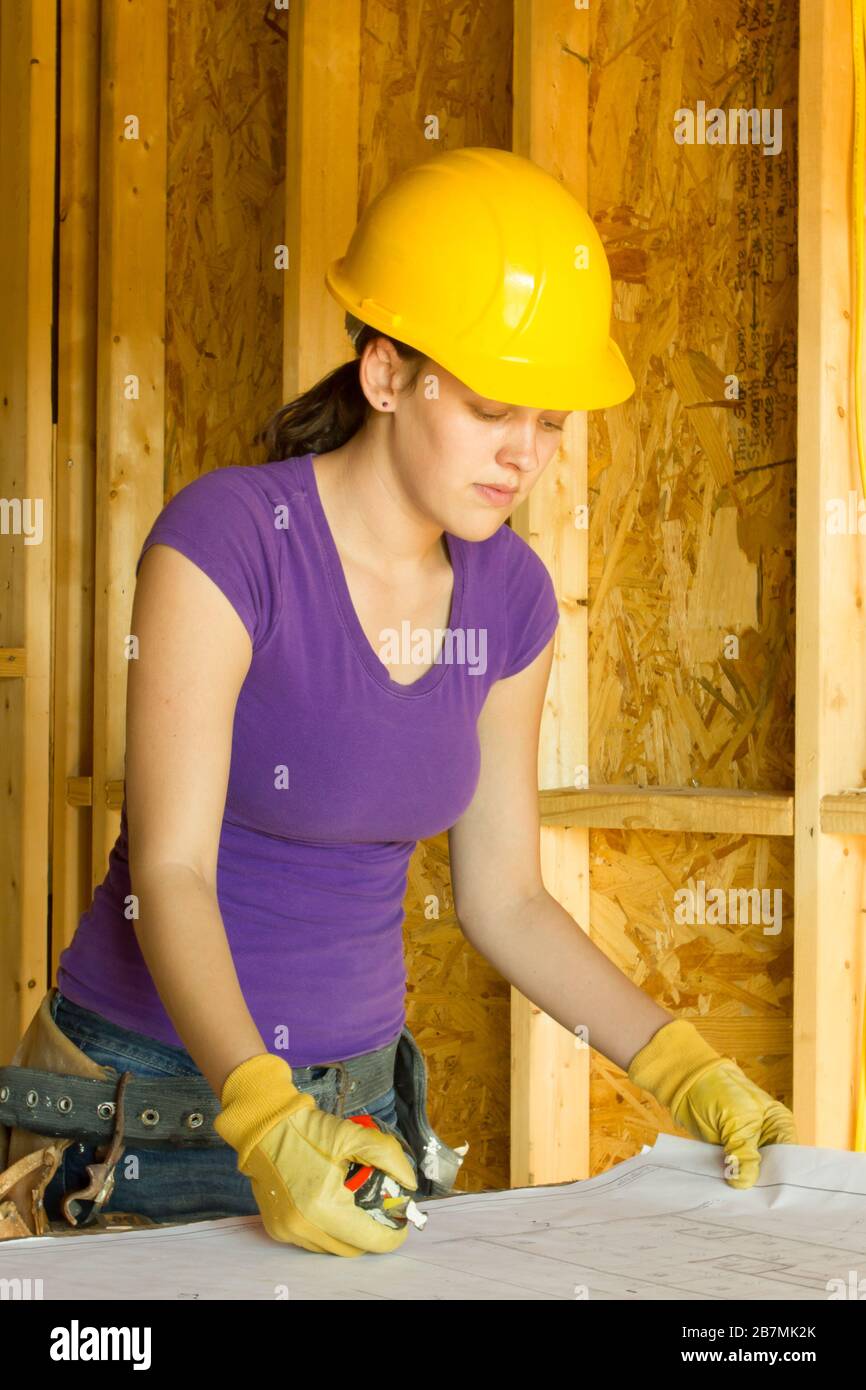 Le jeune ouvrier de la construction féminine passe en revue les dessins d'architecte d'un projet de construction. Généralement perçu comme une industrie dominée par les hommes. Banque D'Images