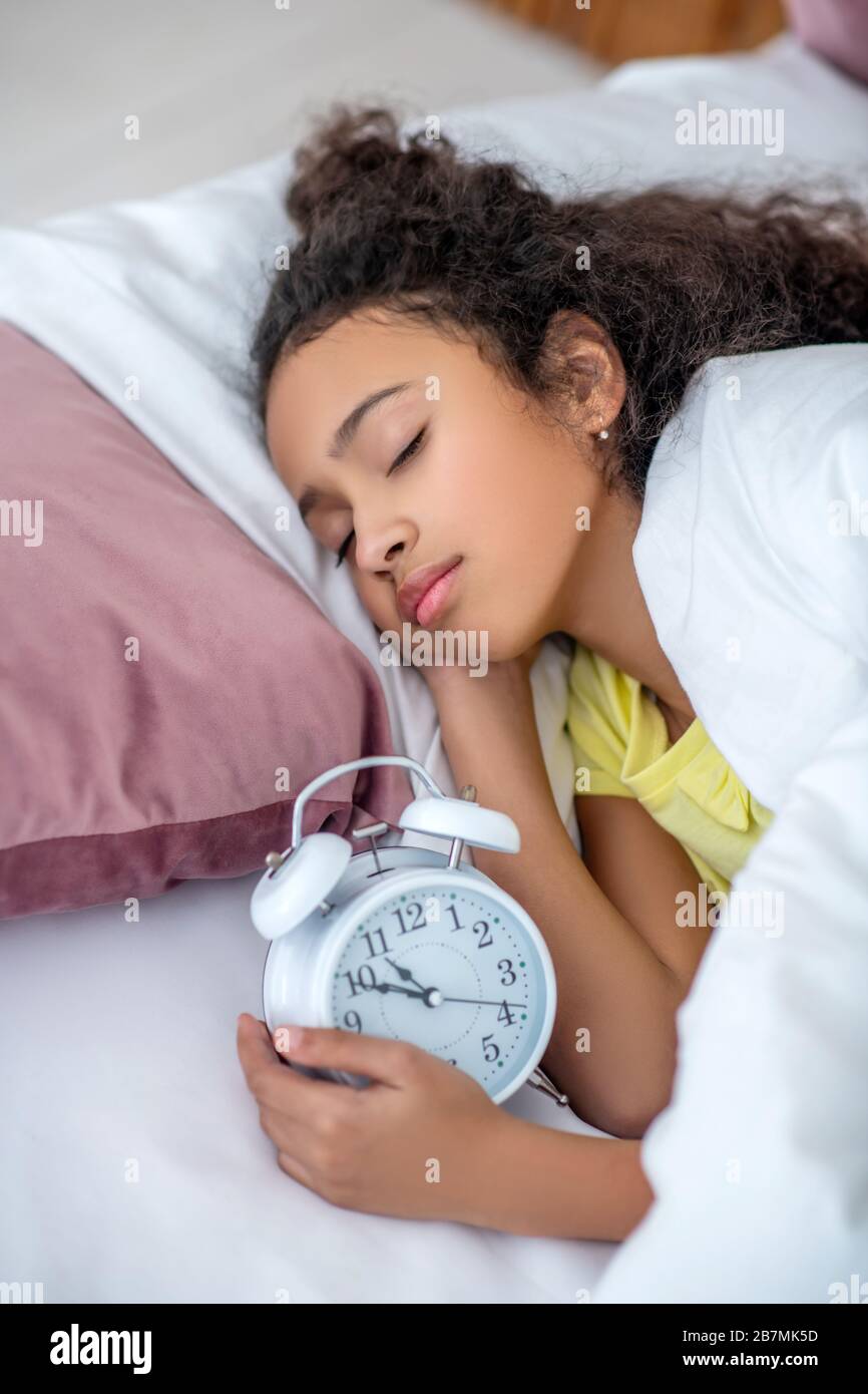 Une adolescente à poil foncé dormant à la maison au lit. Banque D'Images