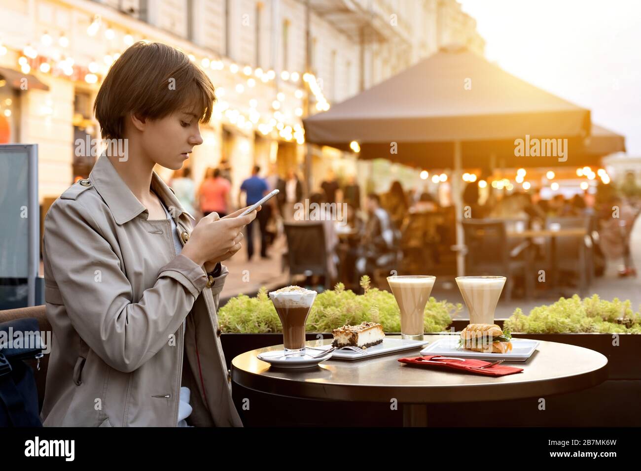 Jeune fille blogger prenant la photo de la nourriture sur le téléphone s'asseoir dans le café de la ville Banque D'Images