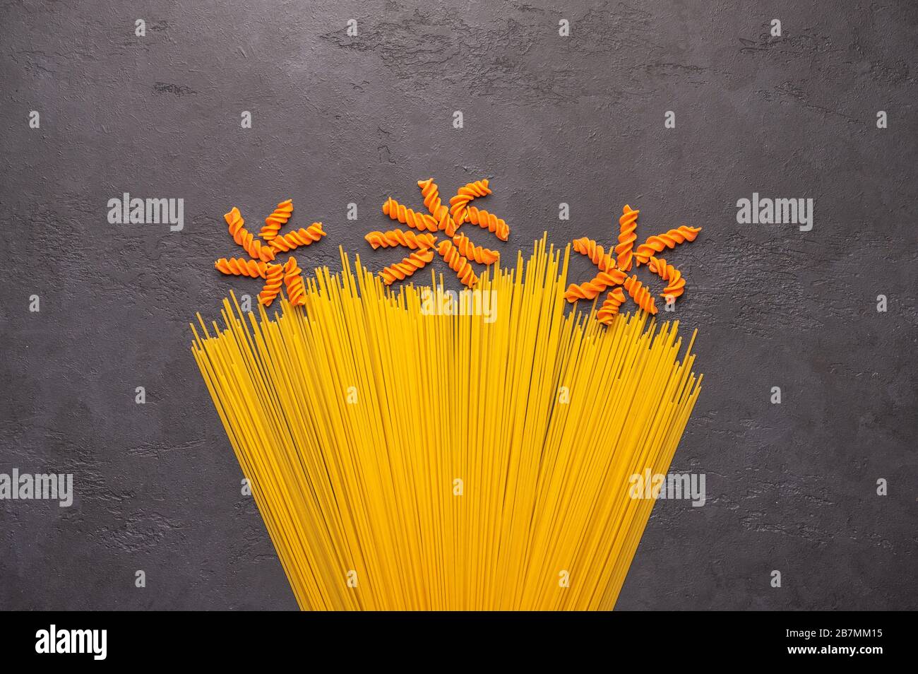 Le concept d'arrière-plan macaroni spaghetti orange et jaune ressemble à une fleur sur fond sombre. Illustration de la cuisine italienne des pâtes Banque D'Images