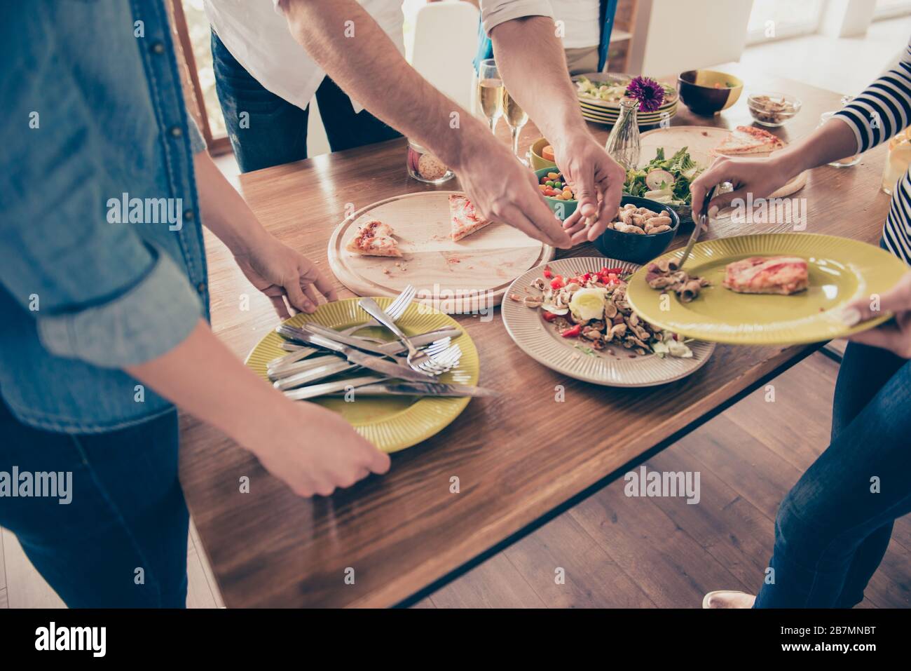 Gros plan photo de personnes timourant la table avec de la nourriture après la fête. Ils le font ensemble, pour être plus rapide et plus amusant Banque D'Images