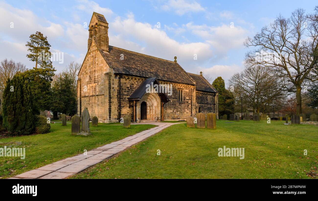 Extérieur de l'église historique de St Jean-Baptiste, des monuments commémoratifs et des sentiers de cour menant à l'arche de porte normande sculptée - Adel, Yorkshire, Angleterre Royaume-Uni Banque D'Images